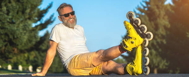 istock The happy old man with a roller skates sitting on the asphalt 1327612896