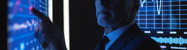 istock The old businessman working on the big blue screen with graphics 1327613068