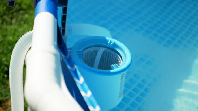 Hand of the worker puts white tablets into pool skimmer. Cleaning, disinfection of water in the swimming pool.