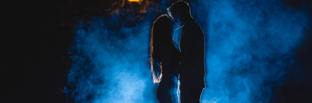 the man and woman kissing on the street on a blue smoke background. night time - street fog profile imagens e fotografias de stock