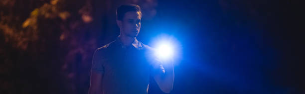 The man stand with a flashlight on the dark alley. night time