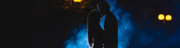 mężczyzna i kobieta całują się na ulicy na niebieskim tle dymu. połów nocny - street fog profile zdjęcia i obrazy z banku zdjęć