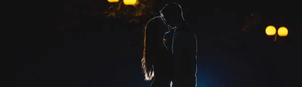 Photo of The couple kissing on the dark alley. night time