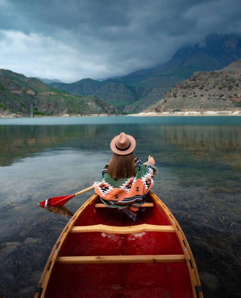 istock Young woman in hat canoeing on a lake 1327614236