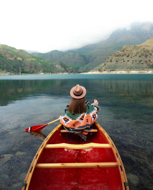 istock Young woman in hat canoeing on a lake 1327614284