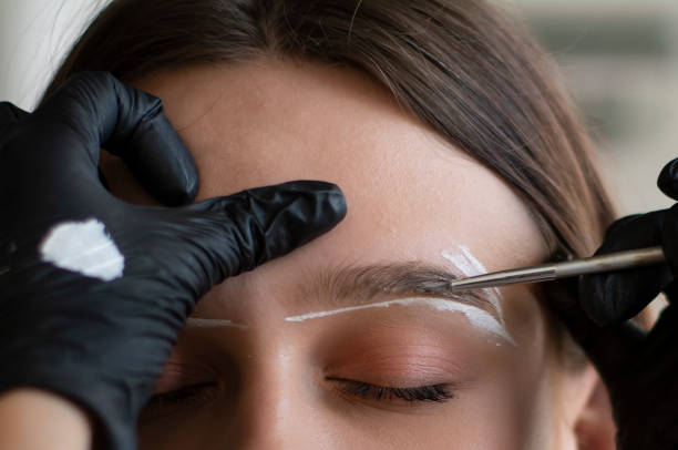 Woman during eyebrow tinting procedure, closeup view Young woman undergoing eyebrow correction procedure in beauty salon, closeup eyebrow stock pictures, royalty-free photos & images