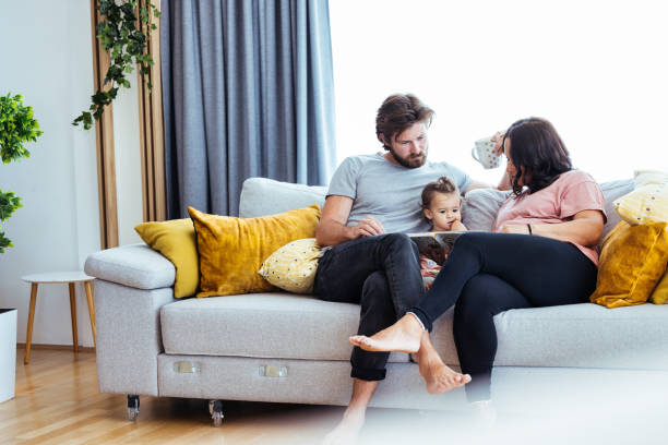 Parents reading a storybook to their toddler Father reading a story from picture book to her baby girl while pregnant mother seated besides them real wife stories stock pictures, royalty-free photos & images