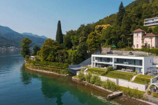 Modern house with direct access to the lake. Aerial drone view from the lake of the house and the landscape surrounding the house. Want to relax and summer.