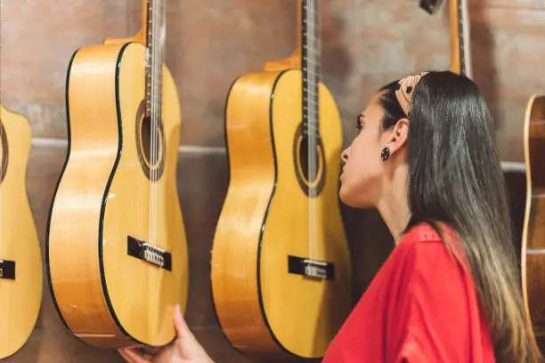 Photo of Woman checking out guitars for purchase