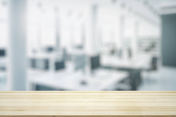 istock Empty wooden table top with light sunny furnished office on background, mock up 1327620360