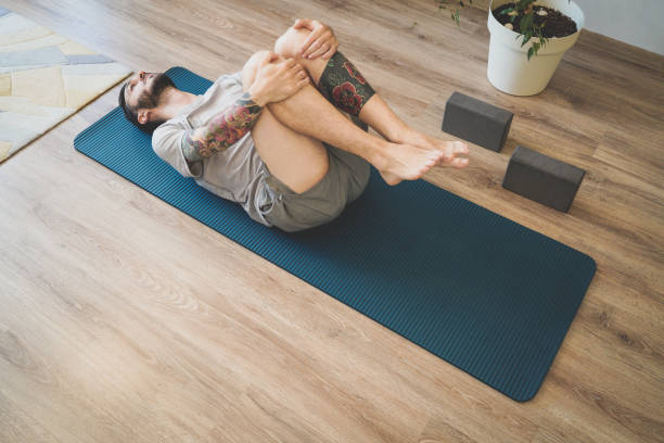 istock Young man starting the day with Wind-Relieving Pose at home 1327621778
