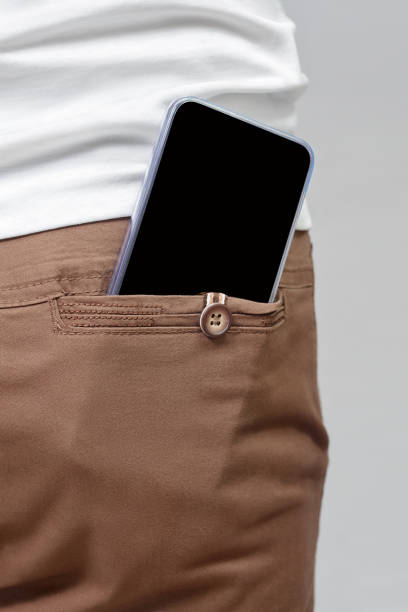 istock Mobile phone with black screen in back pocket of brown pants copy space. 1327621819