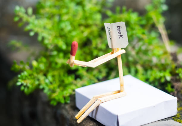 Matchstick concept and ideas. Book reading concept and ideas. Matchstick reading a book with green background.