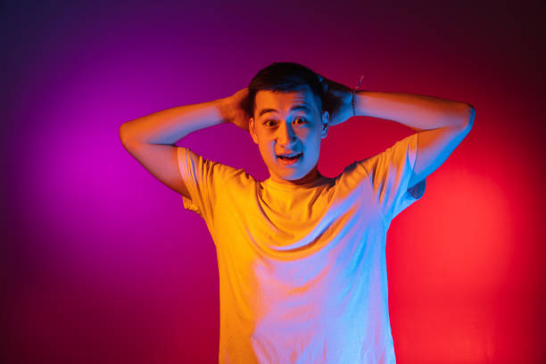 istock One Asian young man posing isolated on studio background in gradient pink purple neon light, colour filter. Concept of human emotions, facial expression. 1327622124