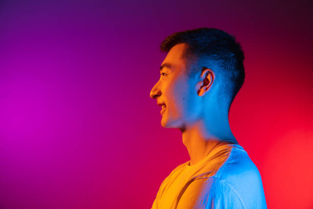istock Side view. Asian young man isolated on studio background in gradient pink purple neon light, colour filter. Concept of human emotions, facial expression. 1327622195
