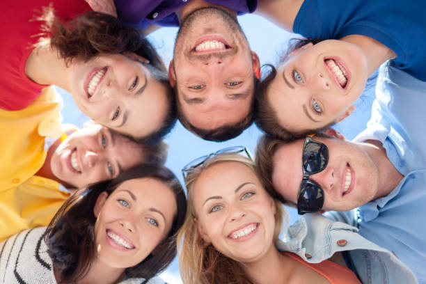 istock smiling friends in circle on summer beach 1327623825