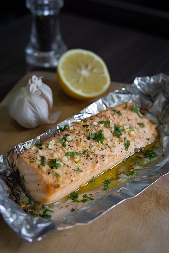 An air fried salmon fillet seasoned with lemon juice, butter, garlic, salt and black pepper. The aluminium foil keeps in the juices of the salmon.