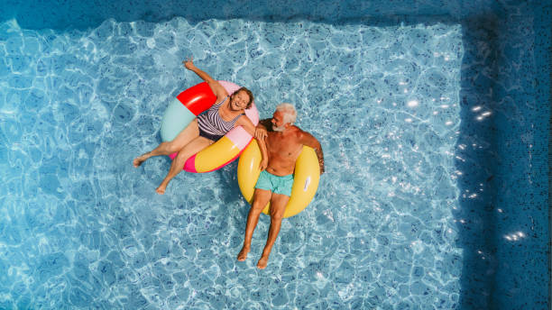 Enjoying our golden years Photo of a senior couple floating on inflatable rings in the swimming pool and enjoying their golden years floating on water stock pictures, royalty-free photos & images