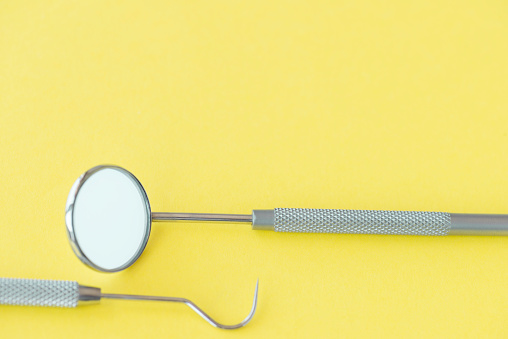 High angle view of dental tools on yellow background.