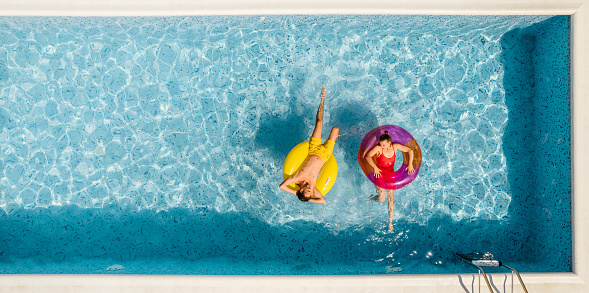 Photo of a couple floating on inflatable rings in the swimming pool