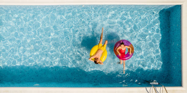 Romantic moments of a couple at the swimming pool Photo of a couple floating on inflatable rings in the swimming pool inflatable ring photos stock pictures, royalty-free photos & images