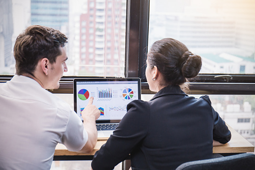 Elegant business partners man and woman listening to colleague at meeting, two business work colleagues discussing online conference. business man with his hand point to the graph