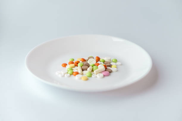 istock Pills on a white plate. Multi-colored pile of pills on a white background. Medication on a white table. Pills under the guise of food on a plate. A pile of tletoks symbolizing food. 1327627992