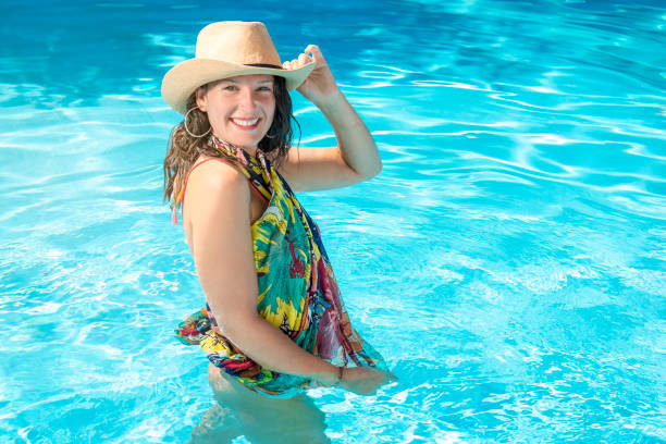 beautiful smiling woman in hat swims in a swimming pool stock photo