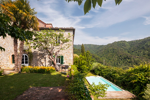 Beautiful Italian farmhouse in Tuscany surrounded by nature with a large garden. The season is summer and the sun is shining.