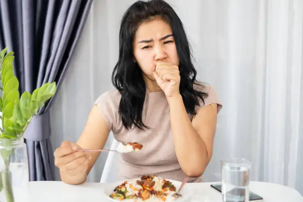 Asian woman choking while eating a meal she has food stuck in the throat and try to vomit