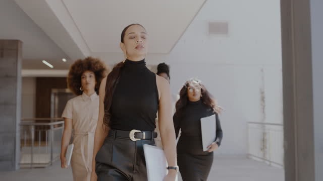 4k video footage of a group of young businesswoman walking through their office building together