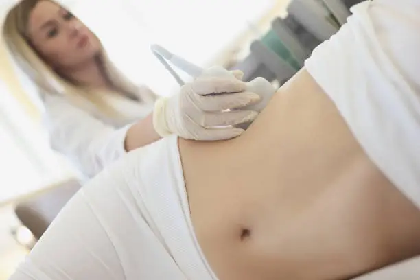 Photo of Doctor doing ultrasound examination of kidneys to woman patient in clinic closeup