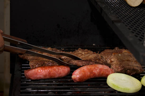 パリラで作られたバーベキュー。ランプステーキ、ソーセージ、オニオンリング。肉を扱う。テキストの空き領域のトップ。 - meat handling ストックフォトと画像