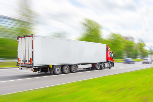 Truck with white trailer driving on city highway with speed motion blur effect