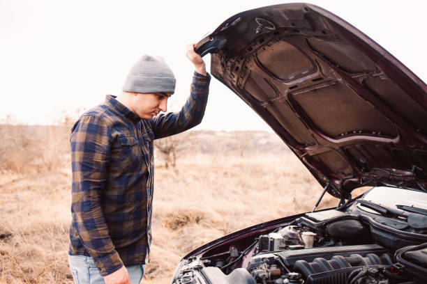 istock Young stressed man having trouble with his broken car looking in frustration at failed engine 1327641696