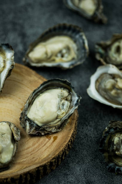 istock Freshly opened oyster on a black stone background. Selective focus 1327643130