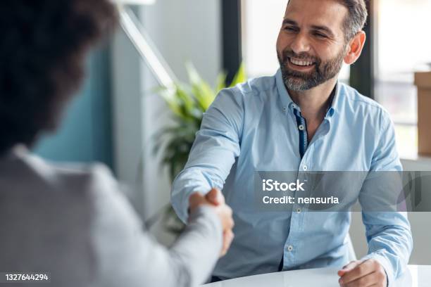 Attractive Realestate Agent Shaking Hands With Young Couple After Signing Agreement Contract In The Office Stock Photo - Download Image Now