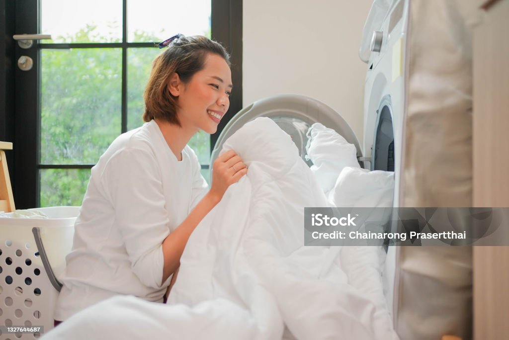 close up young beautiful asian woman smelling the white blanket after finished from wash machine in home for daily and routine lifestyle concept Laundry Stock Photo