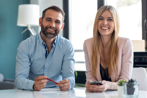 Cute couple explaing something looking at camera while doing video call in the office at home.