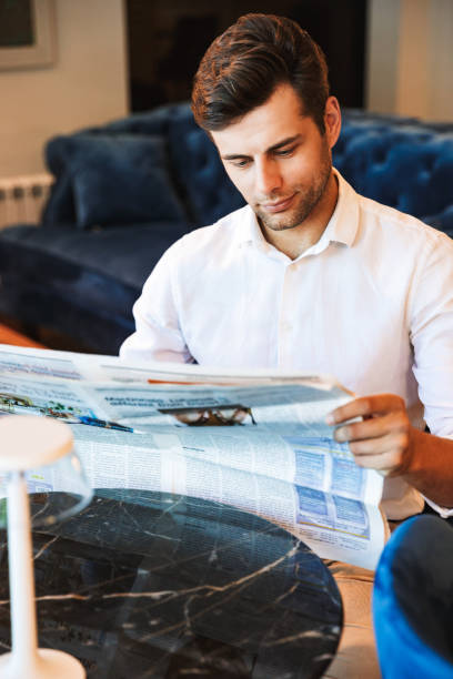 istock Pensive young formal dressed man reading newspaper 1327648060