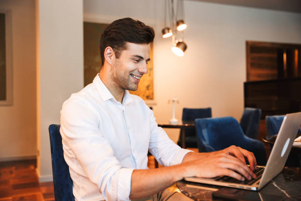 istock Smiling young formal dressed man working on laptop 1327650392