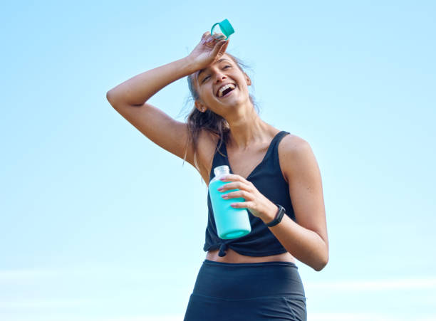 снимок спортивной молодой женщины, пьющей воду во время тренировки на открытом воздухе - women sweat healthy lifestyle exercising стоковые фото и изображения