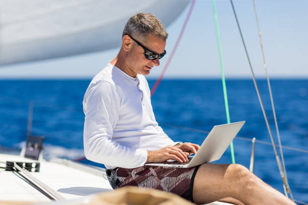 istock Businessman with laptop on sailboat 1327651916