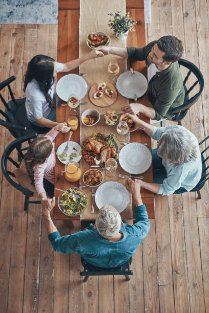 vista superior de la familia multigeneracional tomado de la mano y orando - family thanksgiving dinner praying fotografías e imágenes de stock