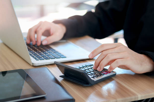 istock Businessman or accountant hands using calculator and laptop computer to calculate financial data, cost and budget on desk at coffee shop or restaurant, accounting statistics and credit analytic for payment. 1327653692
