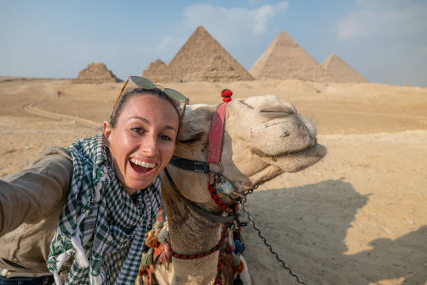 mujer se toma selfie con camello en las pirámides de egipto - tourist egypt pyramid pyramid shape fotografías e imágenes de stock