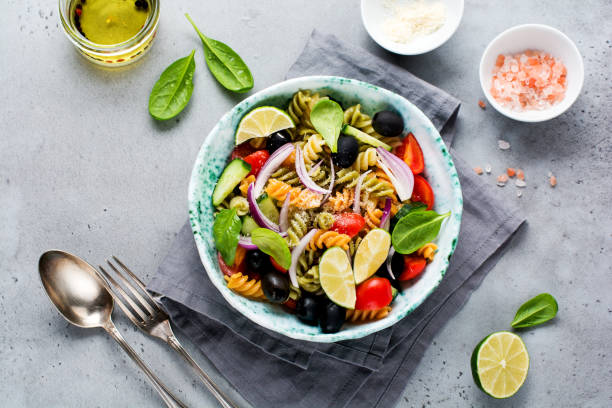 istock Whole grain pasta with vegetables on a white plate on a light grey slate, stone or concrete background. Top view with copy space. 1327654177