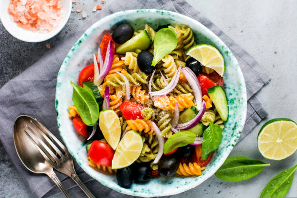 istock Whole grain pasta with vegetables on a white plate on a light grey slate, stone or concrete background. Top view with copy space. 1327655245