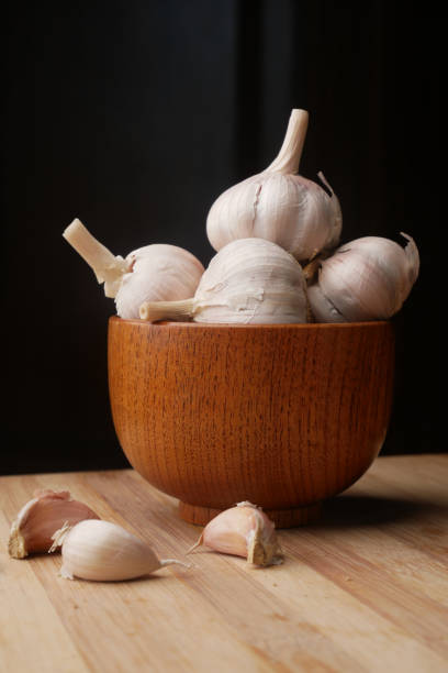 garlic in a wooden bowl on black background, garlic in a wooden bowl on black background,. photography healthcare and medicine studio shot vertical stock pictures, royalty-free photos & images