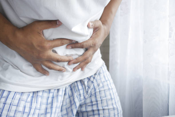 istock young man suffering stomach pain close up. 1327659593